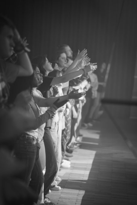 Hände von Menschen, die im Konzert jubeln und klatschen, in Schwarz-Weiß.